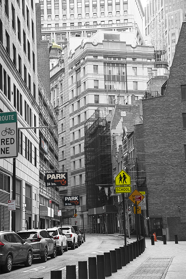 Black and white image, lower Manhattan, with selective parts the image colorized, i.e. car brake lights and street signs